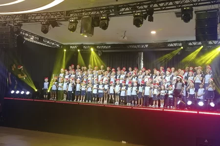 Alunos do Colégio Adventista cantando clássicos de Natal em apresentação emocionante.