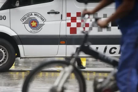 Polícia Militar durante operação na Baixada Santista, com viatura em destaque e policiais armados em patrulha.