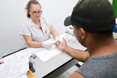 Mesa de testagem rápida de HIV e ISTs com profissionais da saúde atendendo moradores em uma UBS de Mauá durante a campanha "Fique Sabendo".