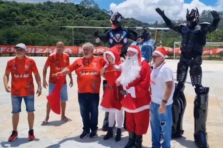 Crianças sorrindo enquanto aguardam a chegada do Papai Noel de helicóptero no Natal Solidário no Campo do Guaraciaba, Santo André