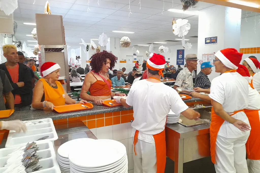 Almoço especial de Natal servido nas unidades do Bom Prato, com frango à parmegiana, macarrão e mini panetone, oferecendo alimentação nutritiva e acessível.