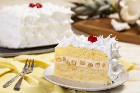 Close dos bolos Abacaxi com Coco e Chocomoça em destaque na promoção Bolos do Mês da Sodiê Doces, com decoração atrativa.