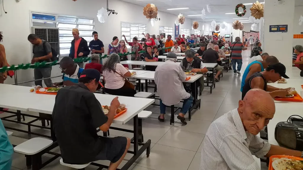 Pessoas sendo atendidas na Caravana da Saúde no Bom Prato Centro, com serviços de assistência e saúde disponíveis gratuitamente.