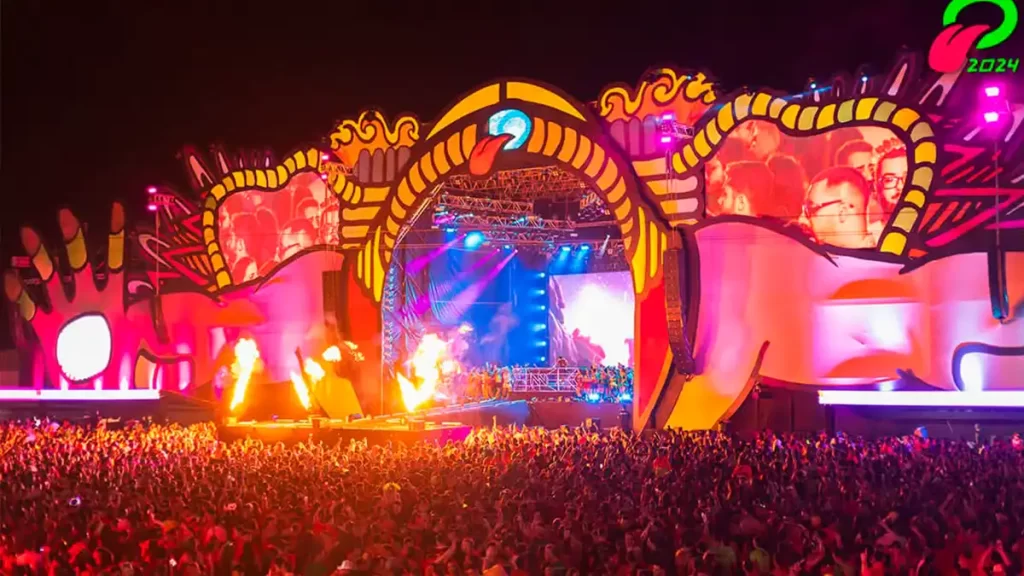 Foliões animados no OBA Festival 2025, com palco iluminado ao fundo.