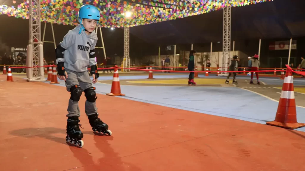 Patinadores fantasiados aproveitam o evento "Patins na Tenda" em Ribeirão Pires, com pista decorada e ambiente festivo.