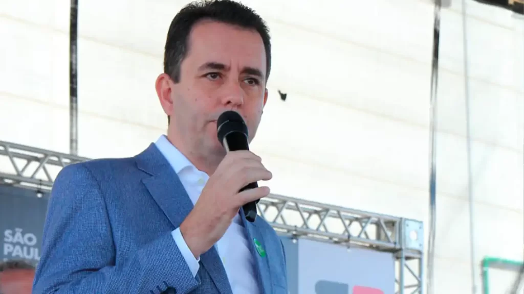 Imagem do governador Tarcísio de Freitas durante evento de campanha, com ele discursando para uma multidão.