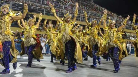 Painel de notas da apuração do Carnaval do Rio 2025, com jurados e representantes das escolas de samba acompanhando a leitura.