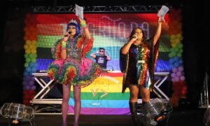 Parada do Orgulho LGBT de Diadema com participantes segurando bandeiras e cartazes na Praça da Moça
